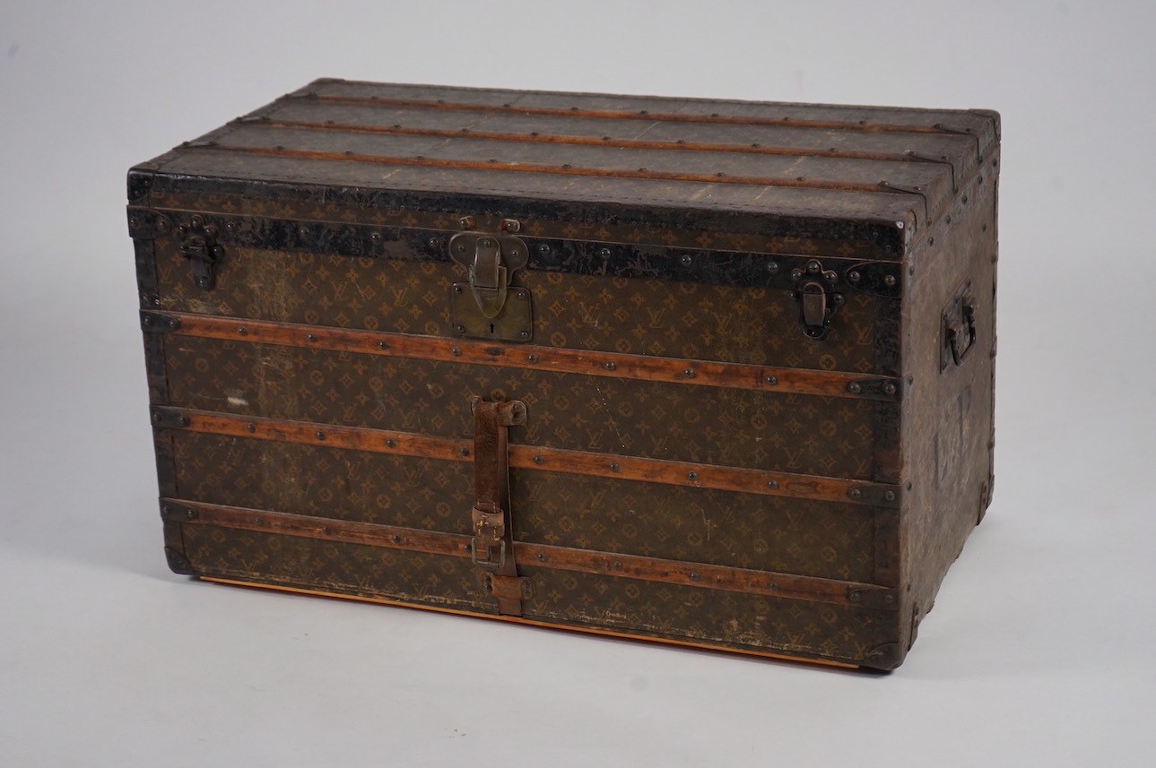 A vintage Louis Vuitton trunk, with wooden slats and black painted steel bound LV canvas, label for Paris, Nice, Lille and London, and numbered stamp 212361, with two internal canvas trays, 100cm wide, 54cm deep, 58cm hi